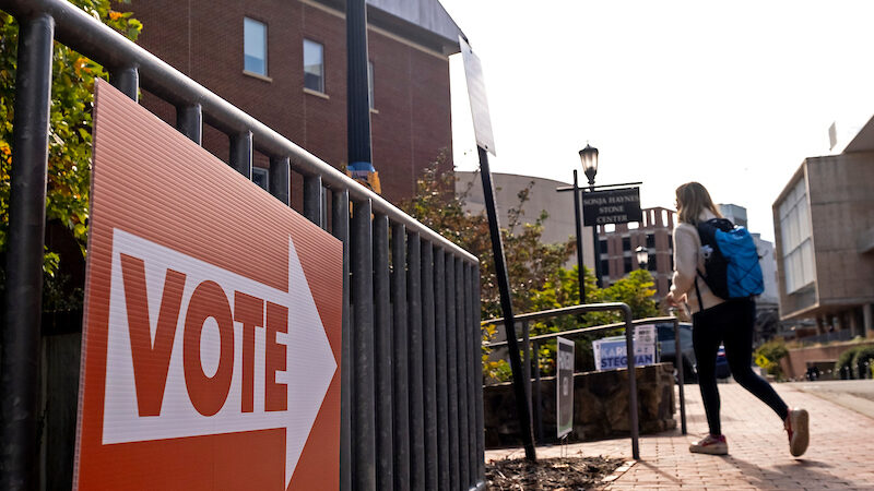 A student walks by a VOTE sign on campus