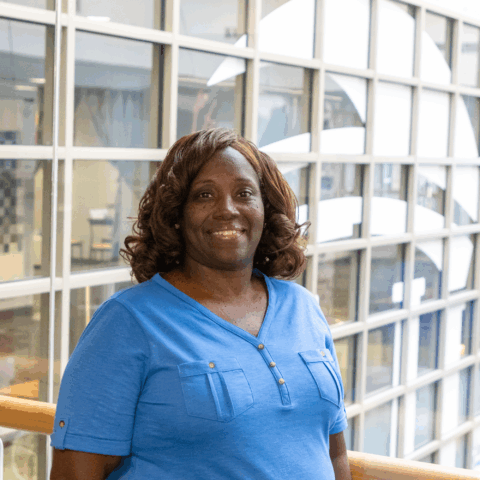 A woman wearing a blue blouse poses for a photo