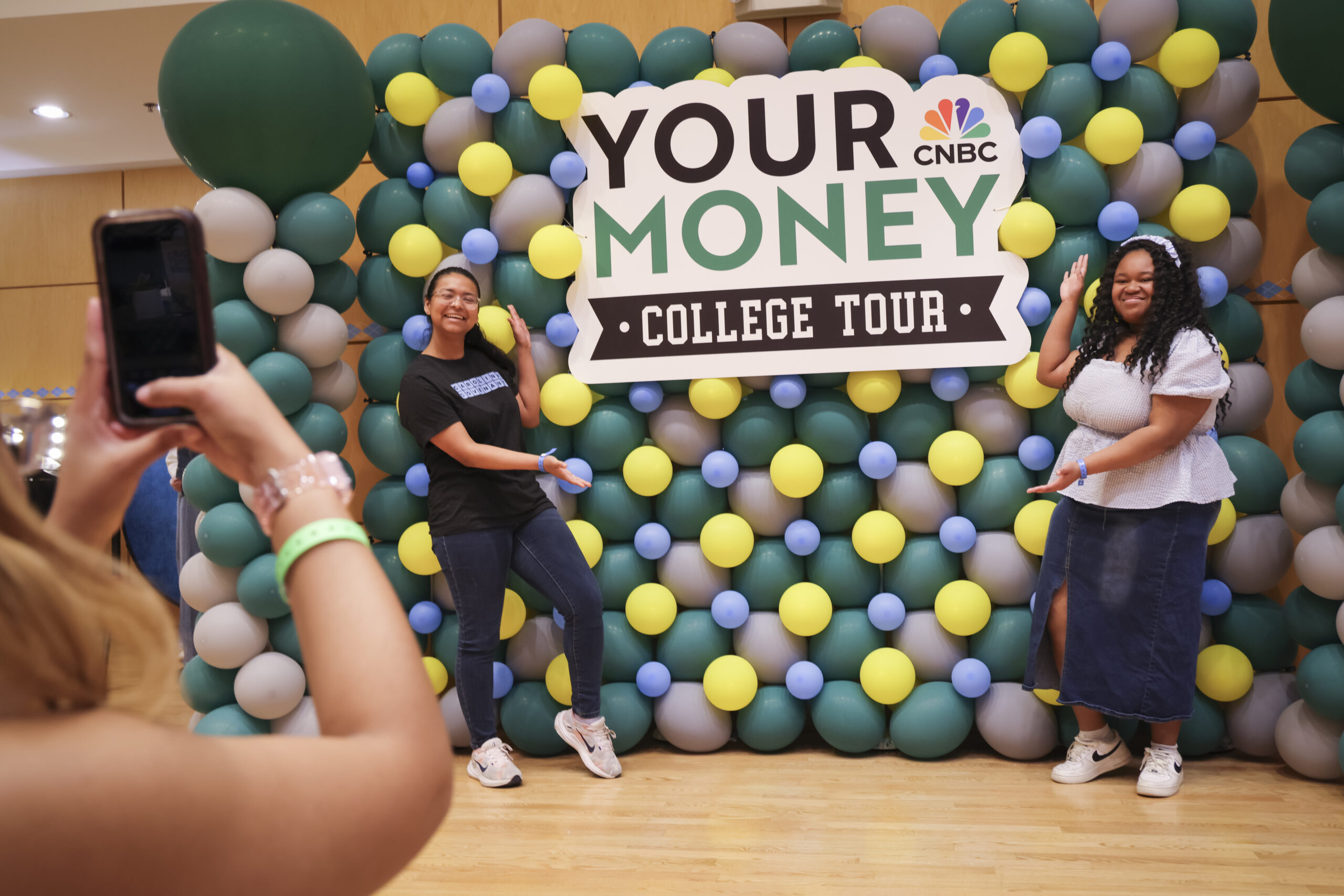 Students stand in front of a balloon wall for the CNBC Your Money Event